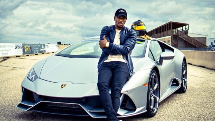 Chauncy Glover posing for a camera with a lavish car in the background